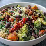 A colorful veggie and quinoa power bowl with roasted seasonal vegetables, black beans, and crunchy nuts drizzled with zesty lemon vinaigrette.