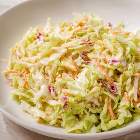 Close-up of homemade coleslaw with visible shredded cabbage and carrots, ready to serve with a meal.