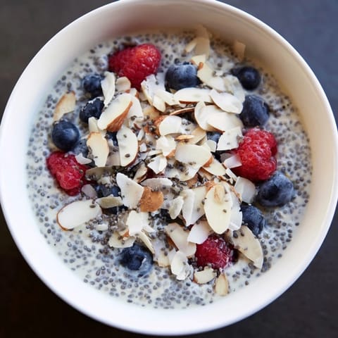 A creamy bowl of Poppy Seed Chia Pudding topped with fresh berries and toasted almonds.
