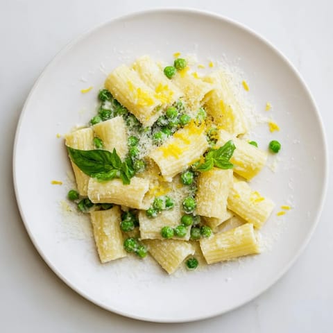 Fresh mint leaves and grated Parmesan garnish a warm bowl of Pea & Lemon Ricotta Pasta, served as a light spring main dish.  