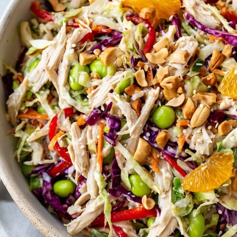 This colorful Edamame Crunch Chicken Salad features tender shredded chicken, crunchy edamame, red cabbage, and red bell peppers, drizzled with a savory-sweet ginger dressing and sprinkled with roasted cashews.