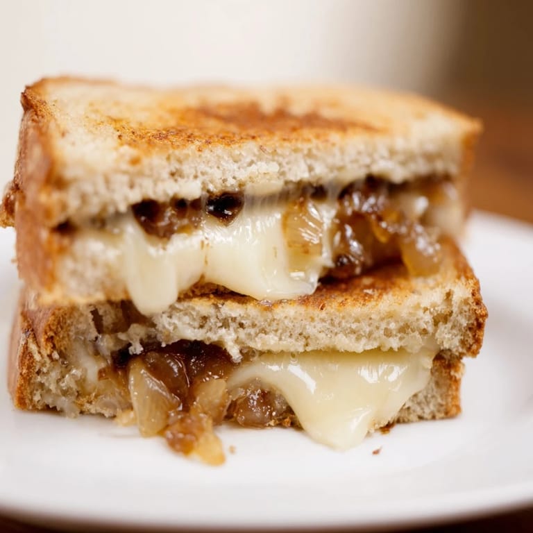 Steaming, melty cheese and jammy onions peek out from buttery, toasted bread of the grilled cheese.