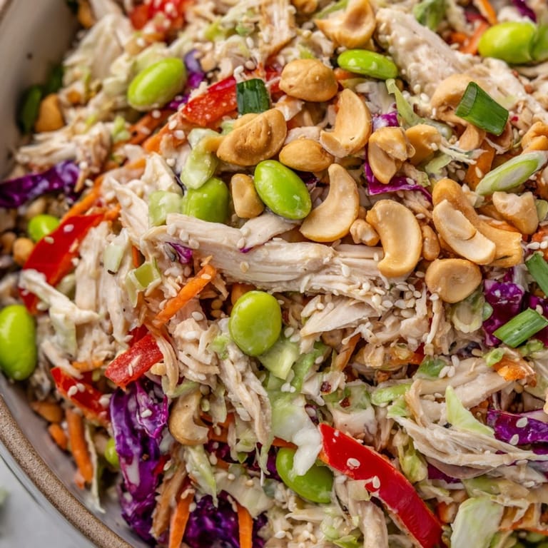A close-up of Edamame Crunch Chicken Salad in a white bowl, highlighting the green edamame, orange carrots, and fresh ginger dressing, ready to serve as a light, healthy dinner.