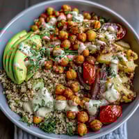 A vibrant Chickpea Power Bowl with roasted vegetables, spiced chickpeas, and creamy tahini sauce on a bed of quinoa.  