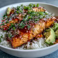 Vibrant 15-minute teriyaki salmon bowl with glazed salmon, fresh cucumber, avocado, and sesame seeds over jasmine rice.