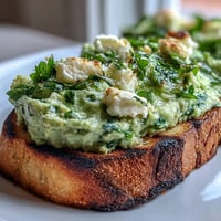 Vibrant fava bean and mint bruschetta atop smoky grilled sourdough, a perfect spring appetizer.