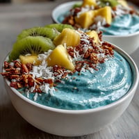 VIBRANT Blue Spirulina Smoothie Bowl with tropical fruit slices and granola highlights.